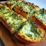 Aufgeschnittenes Cheesy Pesto Garlic Bread mit geschmolzenem K&auml;se und gr&uuml;ner Pesto-Kruste.