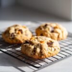 Drei frisch gebackene Chocolate Butterscotch Cookies auf einem schwarzen Drahtgitter.