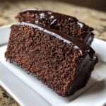 Nahaufnahme von zwei saftigen Scheiben Chocolate Fudge Cake mit gl&auml;nzender dunkler Schokoladenglasur.