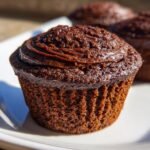 Nahaufnahme eines saftigen Chocolate Sweet Potato Cupcakes mit dunkler Schokoladencreme.
