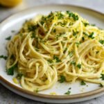 Nahaufnahme von cremiger Lemon Pasta, garniert mit frischem Zitronenabrieb und gehackter Petersilie auf einem Teller.