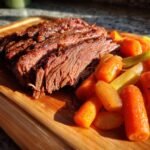 Aufgeschnittenes, zartes Crock Pot Corned Beef mit glasierten Karotten auf einem Holzbrett.