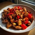 Nahaufnahme von Easy Kung Pao Chicken mit Cashewn&uuml;ssen und roten Paprikast&uuml;cken in einer dunklen So&szlig;e.