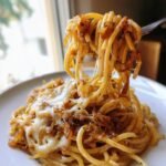 Gabel mit geschmolzenem K&auml;se und karamellisierten Zwiebeln, die French Onion Pasta hochzieht.