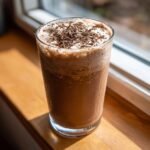Ein kaltes Frozen Chocolate Brandy Alexander in einem hohen Glas mit Schlagsahne und Schokostreuseln.