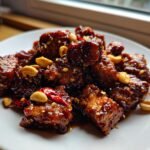 Nahaufnahme von knusprigem Kung Pao Tofu, glasiert und garniert mit Erdn&uuml;ssen und Chili.