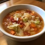 Eine Sch&uuml;ssel mit herzhafter Krautsuppe, gef&uuml;llt mit Kohlst&uuml;cken, Karotten und Tomaten.