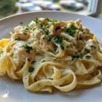 Nahaufnahme von cremigem Lemon Chicken Fettuccine mit H&auml;hnchenst&uuml;cken und Petersilie garniert.