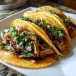 Nahaufnahme von drei Quick Pork Carnitas Tacos mit saftigem Fleisch, Koriander und Zwiebeln auf Maistortillas.