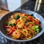 Nahaufnahme von leckerem Shrimp Lo Mein mit gebratenen Garnelen, Brokkoli, Karotten und roter Paprika in einer Sch&uuml;ssel.