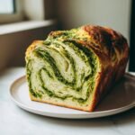 Aufgeschnittenes Slow Cooker Basilikum Pesto Brot mit deutlicher gr&uuml;ner Spiralstruktur.