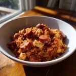 Eine wei&szlig;e Sch&uuml;ssel gef&uuml;llt mit w&uuml;rzigem Slow Cooker Cajun Jambalaya mit Reis, Huhn und viel Chorizo.