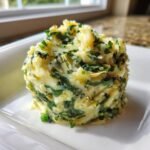 Eine Portion cremiger Spinach And Artichoke Mashed Potatoes, garniert mit viel gr&uuml;nem Spinat und Artischockenst&uuml;ckchen.