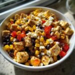 Nahaufnahme einer Sch&uuml;ssel Tex Mex Chicken Salad mit gew&uuml;rfeltem H&auml;hnchen, Mais, schwarzen Bohnen und zerbr&ouml;seltem K&auml;se.