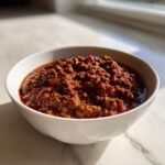 Nahaufnahme von reichhaltigem Texas No Beans Chili mit viel Hackfleisch in einer wei&szlig;en Sch&uuml;ssel.
