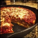 Aufgeschnittene Whole Wheat Deep Dish Skillet Pizza in einer gusseisernen Pfanne mit dicker Tomatensauce und geschmolzenem K&auml;se.