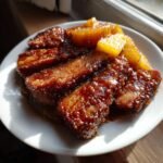 Gebratene Scheiben von Spam in einer dunklen, gl&auml;nzenden Glasur, serviert mit karamellisierten Ananasst&uuml;cken. Ein Beispiel f&uuml;r geniale Spam Recipes.