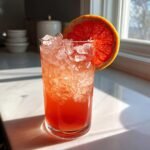 Nahaufnahme eines erfrischenden Grapefruit Aperol Spritz Mocktail mit zersto&szlig;enem Eis und einer Grapefruit-Scheibe.