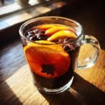 Dampfender Mulled Wine in einer Glastasse mit Orangenscheiben und Sternanis.