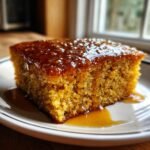 Ein St&uuml;ck saftiges Hot Honey Southern Cornbread, &uuml;bergossen mit gl&auml;nzendem Honig auf einem wei&szlig;en Teller.
