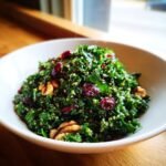 Nahaufnahme eines gesunden Kale Quinoa Salat mit getrockneten Cranberrys und Waln&uuml;ssen in einer wei&szlig;en Sch&uuml;ssel.