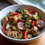 Nahaufnahme von Keto Sausage Recipes: Fleischb&auml;llchen und Wurstscheiben mit Brokkoli, Paprika und Pilzen in cremiger So&szlig;e.