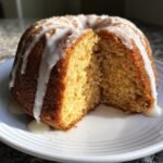 Ein angeschnittener Lemon Ginger Bundt Cake mit cremigem Zuckerguss, der &uuml;ber den Rand tropft.