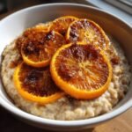 Nahaufnahme von Maple Cinnamon Oatmeal mit karamellisierten Orangen Scheiben in einer wei&szlig;en Sch&uuml;ssel.