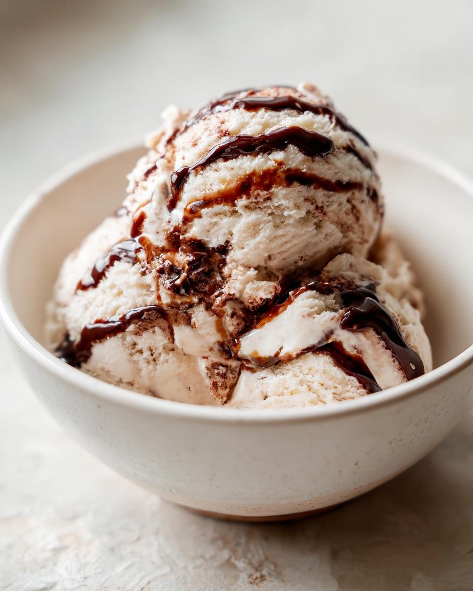 Zwei Kugeln Mocha Latte Frozen Yogurt mit dunkler Schokoladensauce in einer wei&szlig;en Schale.