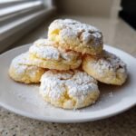 Ein Stapel m&uuml;rber Lemon Cookies, dick mit Puderzucker best&auml;ubt, auf einem wei&szlig;en Teller.