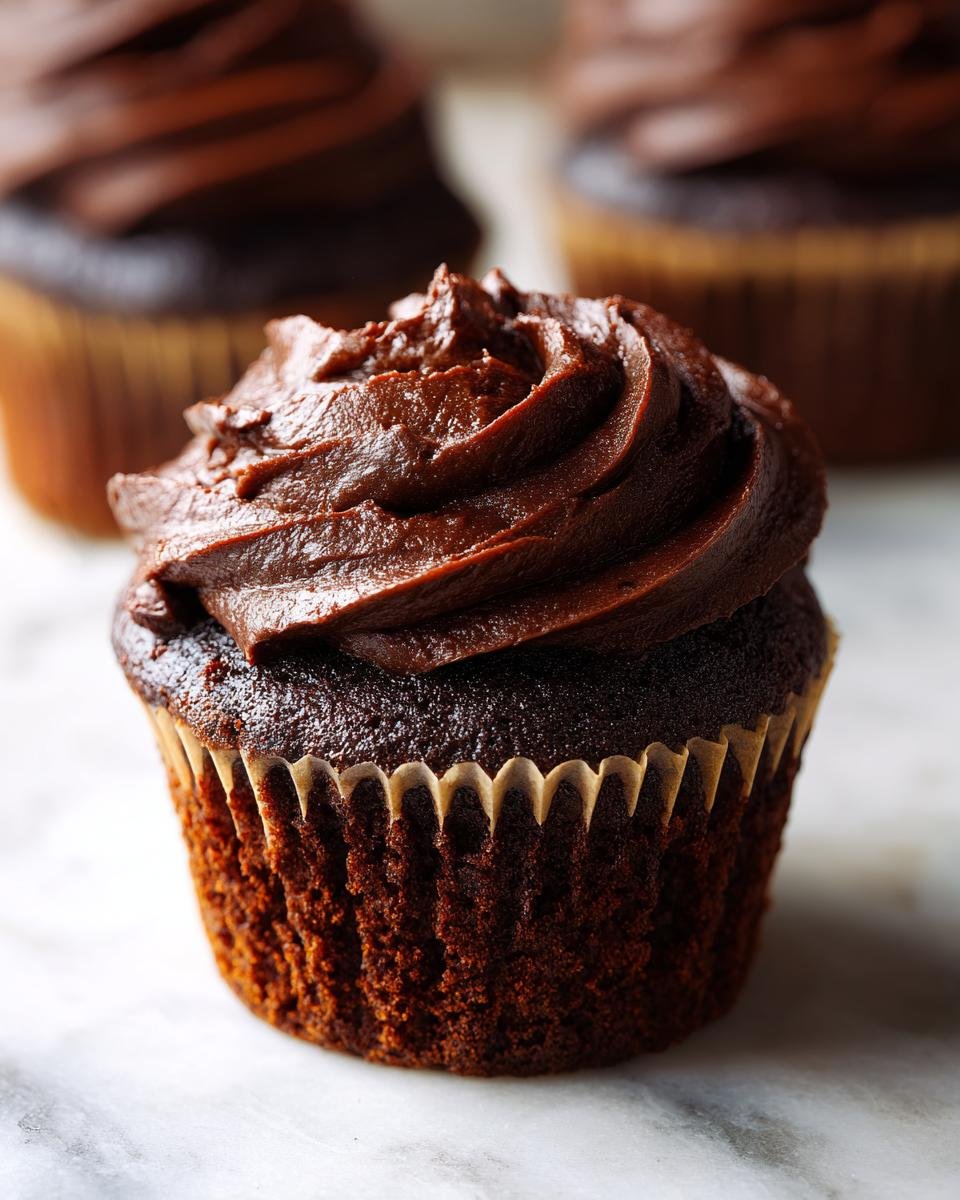 Nahaufnahme eines saftigen Spooky Double Chocolate Cupcakes mit dunkler Schokoladencreme.