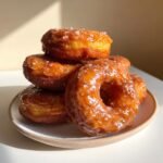 Stapel von Salted Caramel Glazed Pumpkin Donuts, gl&auml;nzend glasiert und mit grobem Salz bestreut.