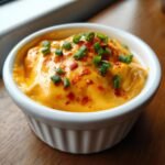 Nahaufnahme eines cremigen, orangefarbenen Velveeta Recipes Dips, garniert mit Schnittlauch und Chiliflocken.