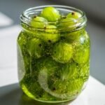 Nahaufnahme von gr&uuml;nen Stachelbeeren in einer Glasmarmelade, die im Licht gl&auml;nzt.