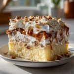 Nahaufnahme eines St&uuml;cks Heath Bar Cake mit hellem Biskuitboden, Sahne und Karamell-Topping.