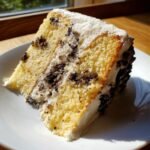Nahaufnahme eines Kuchenschnitts vom Vegan Vanilla Oreo Cake mit gelbem Biskuit und wei&szlig;er Creme.