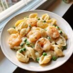 Nahaufnahme von White Cheddar Shells Mit Garnelen und Erbsen in cremiger K&auml;sesauce.