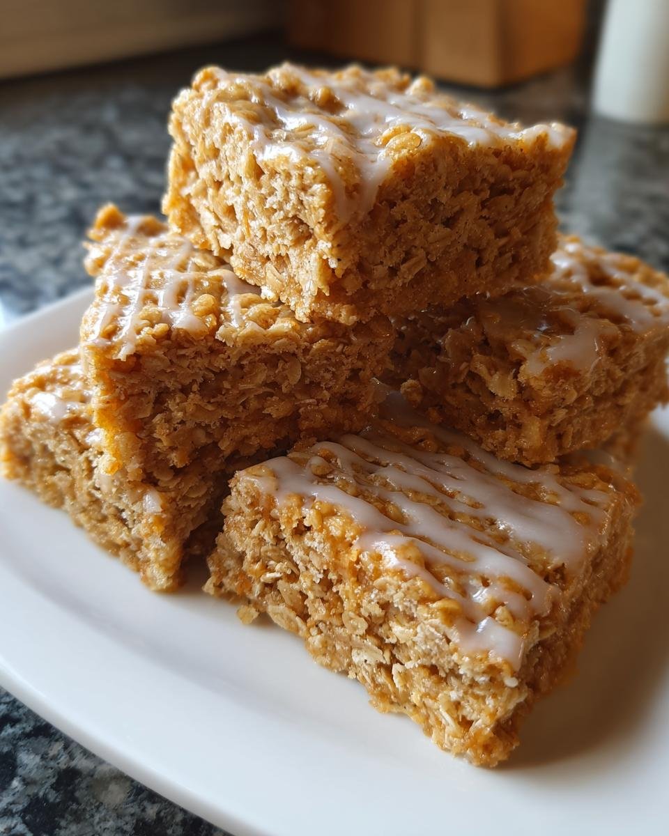Stapel von z&auml;hen, haferflockenreichen Flapjacks, betr&auml;ufelt mit wei&szlig;em Zuckerguss.