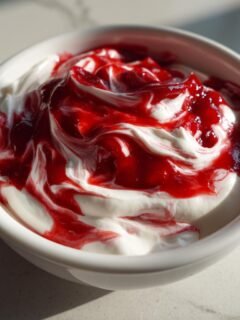 Nahaufnahme von cremigem Cherry Cheesecake Dip mit rotem Kirschswirl in einer weißen Schale.