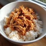 Nahaufnahme von Chicken Rice Bowls mit wei&szlig;em Reis und zerfasertem, w&uuml;rzigem H&auml;hnchen.