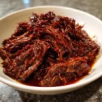 Nahaufnahme von saftigem, zerfasertem Chipotle Barbacoa in einer wei&szlig;en Sch&uuml;ssel.