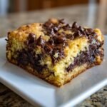 Nahaufnahme eines saftigen St&uuml;cks Chocolate Chip Sheet Cake mit geschmolzenen Schokoladenst&uuml;ckchen obenauf.