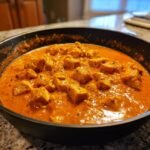 Nahaufnahme von w&uuml;rfeligem H&auml;hnchen in einer cremigen, orangefarbenen So&szlig;e im Easy Butter Chicken Skillet.