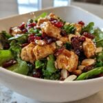 Nahaufnahme eines Frischer Asiatischer H&auml;hnchen-Cranberry-Salat in einer wei&szlig;en Sch&uuml;ssel mit glasiertem H&auml;hnchen.