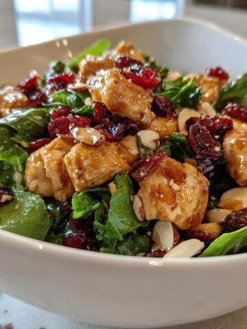 Nahaufnahme eines Frischer Asiatischer Hähnchen-Cranberry-Salat in einer weißen Schüssel mit glasiertem Hähnchen.