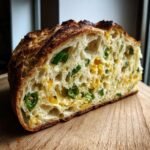 Aufgeschnittenes Irresistible Jalapeno Cheddar Sauerteigbrot mit sichtbaren Jalapeno-Scheiben und K&auml;se.