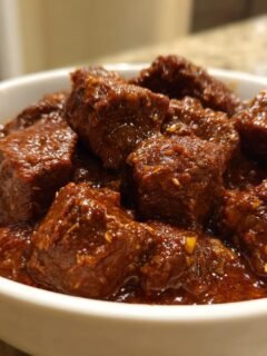 Nahaufnahme von saftigen Fleischst&uuml;cken in einer tiefroten Sauce, typisch f&uuml;r Paula Deens Goulash.