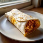 Ein fertiger Wrap gef&uuml;llt mit H&auml;hnchen und geschmolzenem K&auml;se, ein Beispiel f&uuml;r Quick And Cheesy Garlic Chicken Wraps.