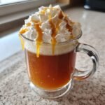 Ein Glas Starbucks Caramel Apple Cider, gekr&ouml;nt mit Schlagsahne und Karamellso&szlig;e.