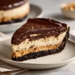 Nahaufnahme eines St&uuml;cks Decadent Chocolate Peanut Butter Temptation Pie mit Schokoladenkruste und mehreren Schichten.